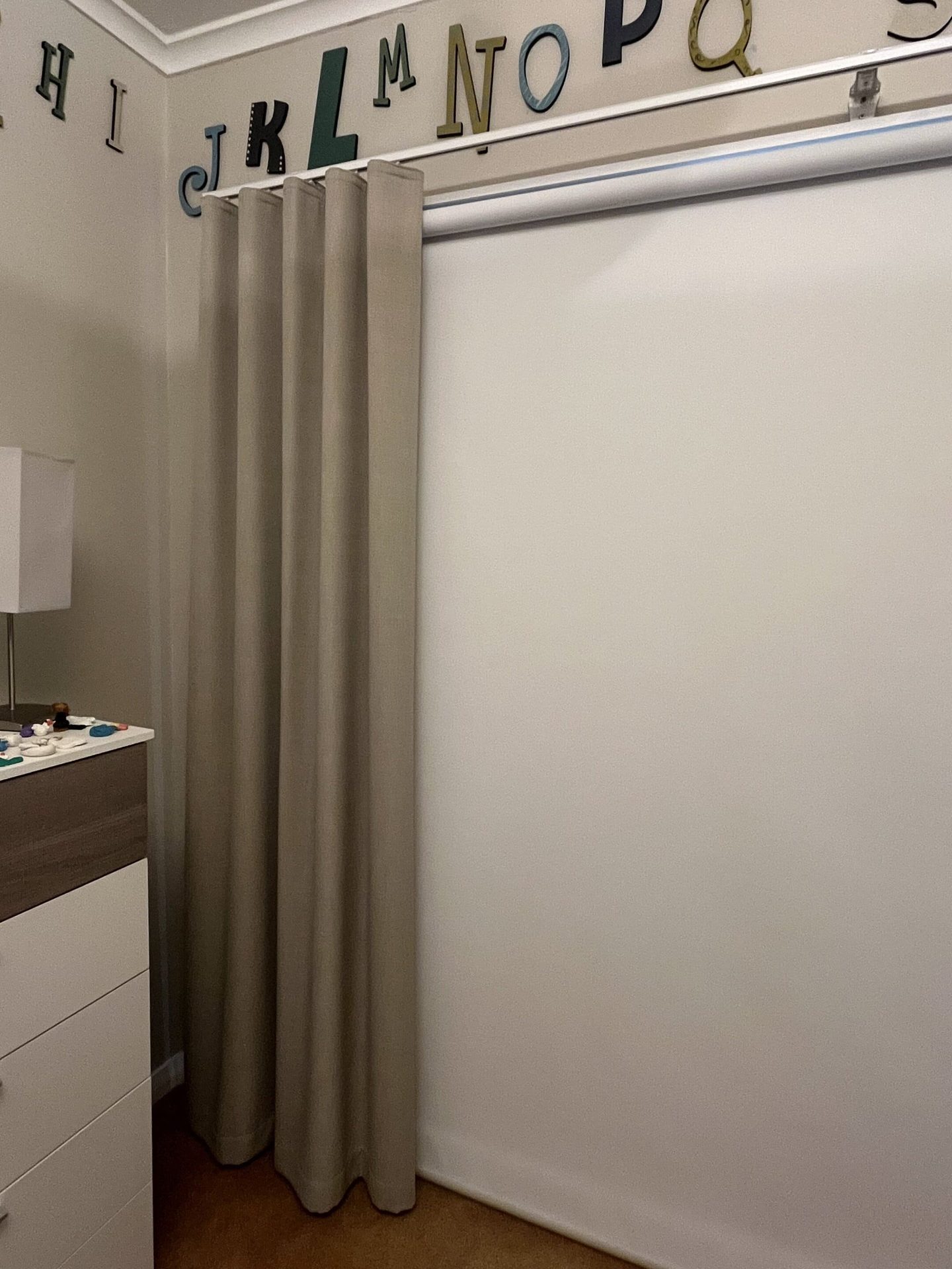 Blockout S-Fold curtains hanging in even folds beside a bed