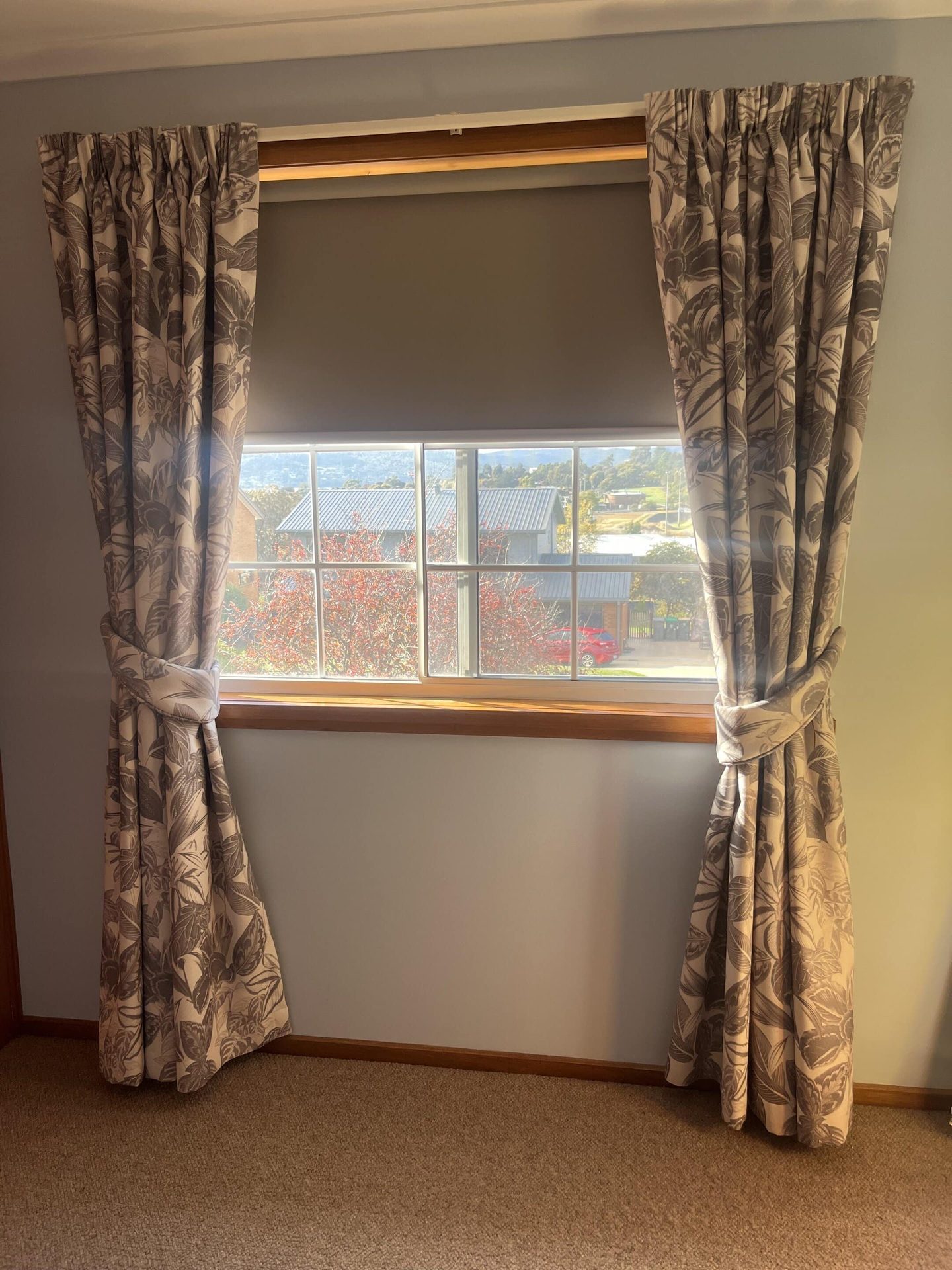 Pencil pleat curtains gathered beside a bedroom window