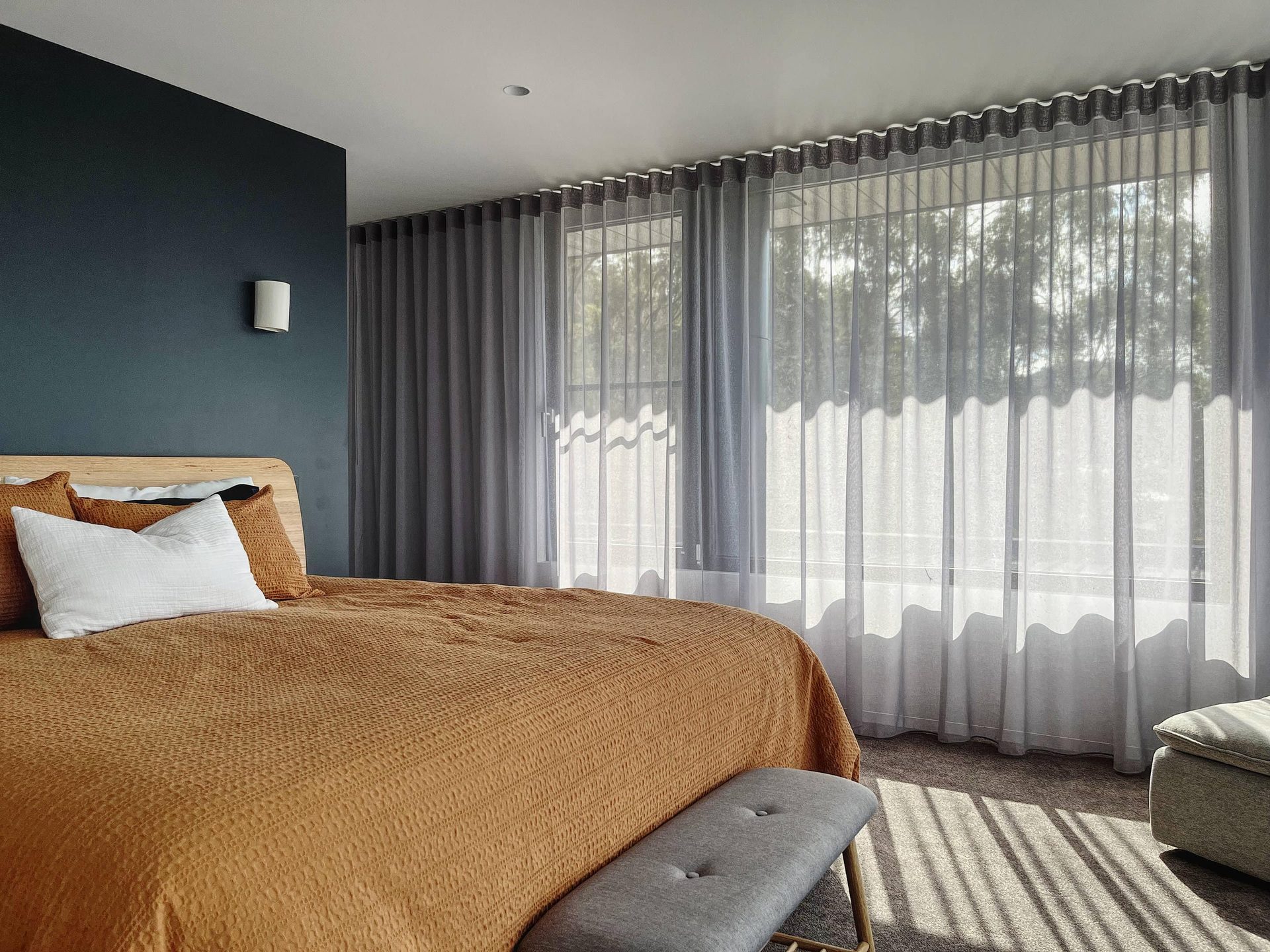 Sheer curtains filtering afternoon light across a bedroom window