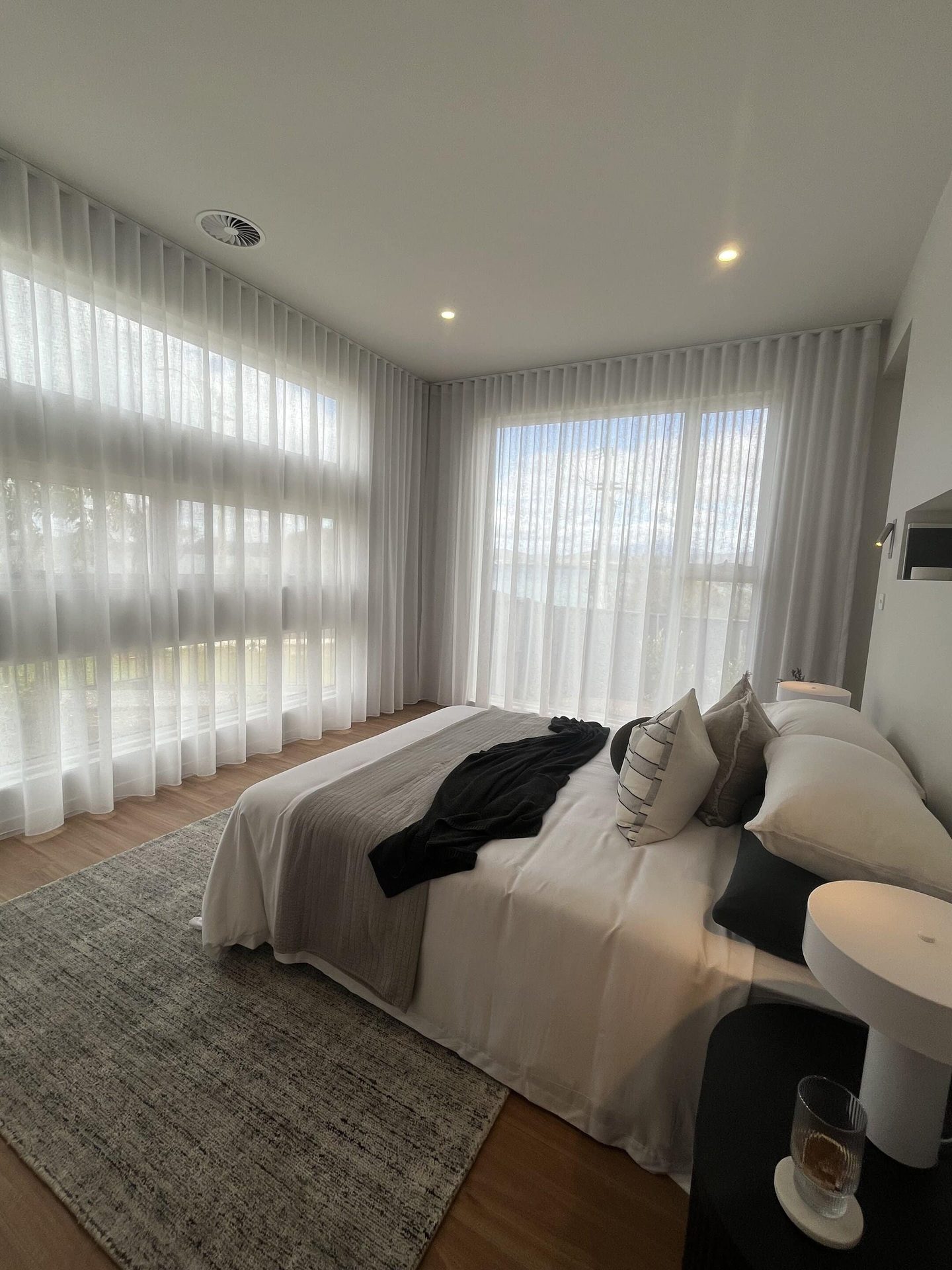 Bedroom with sheer curtains and a blockout blind behind the bedhead