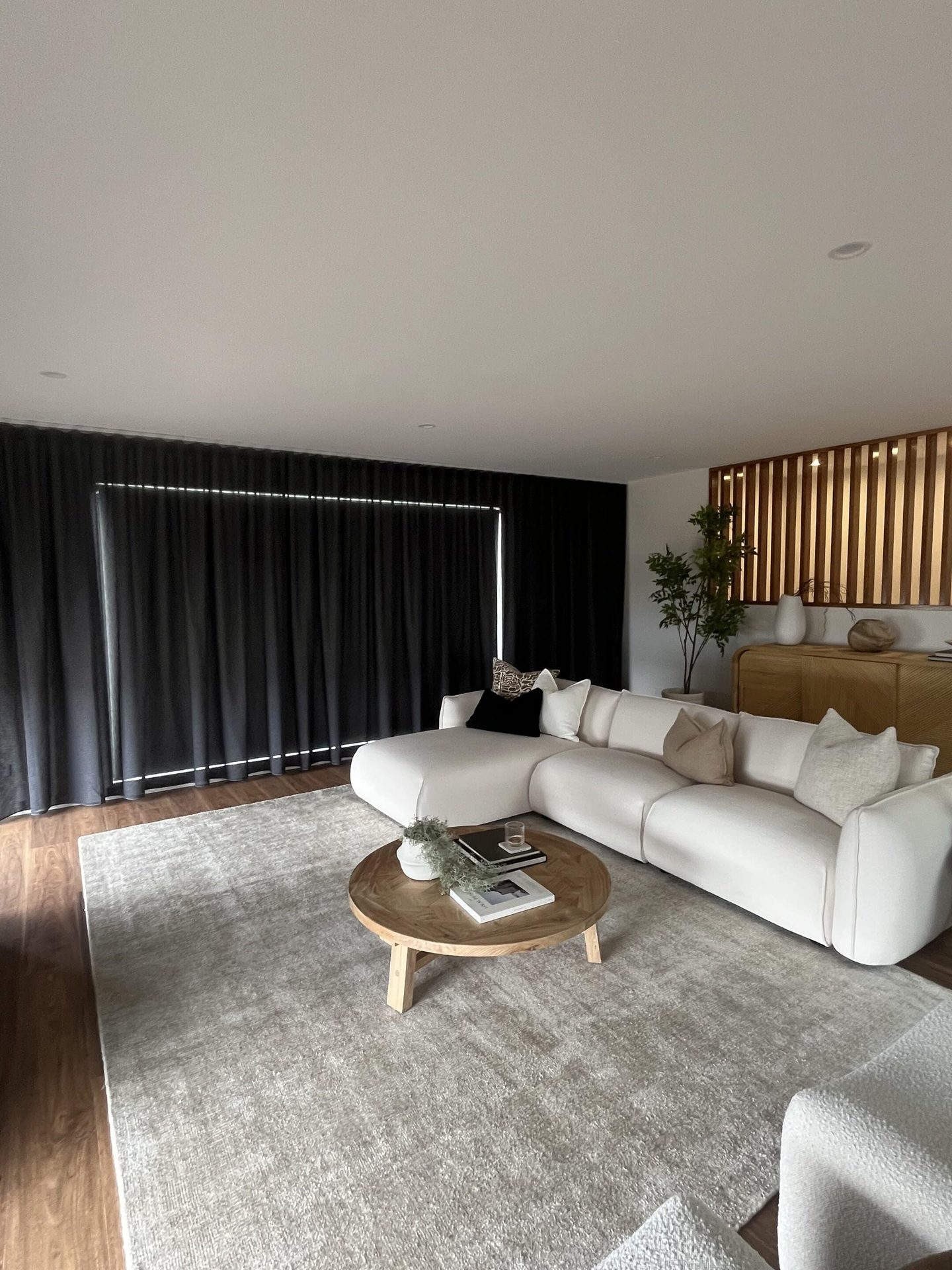 Living room with floor to ceiling sheer curtains and a timber floor