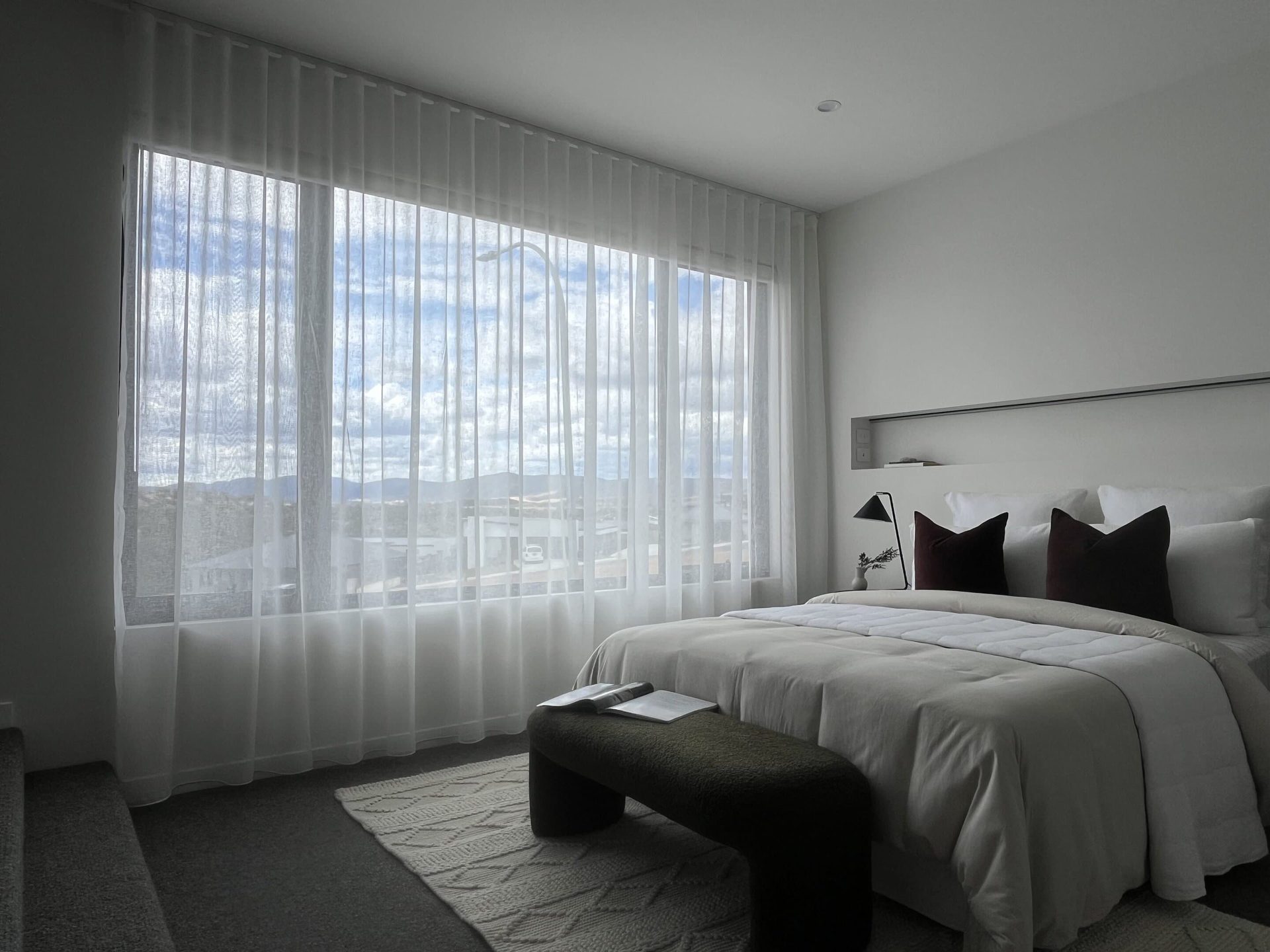 Bedroom with wall to wall sheer curtains across a wide window